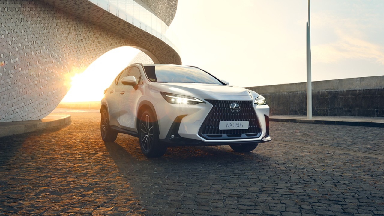A parked Lexus NX with its LED headlights on